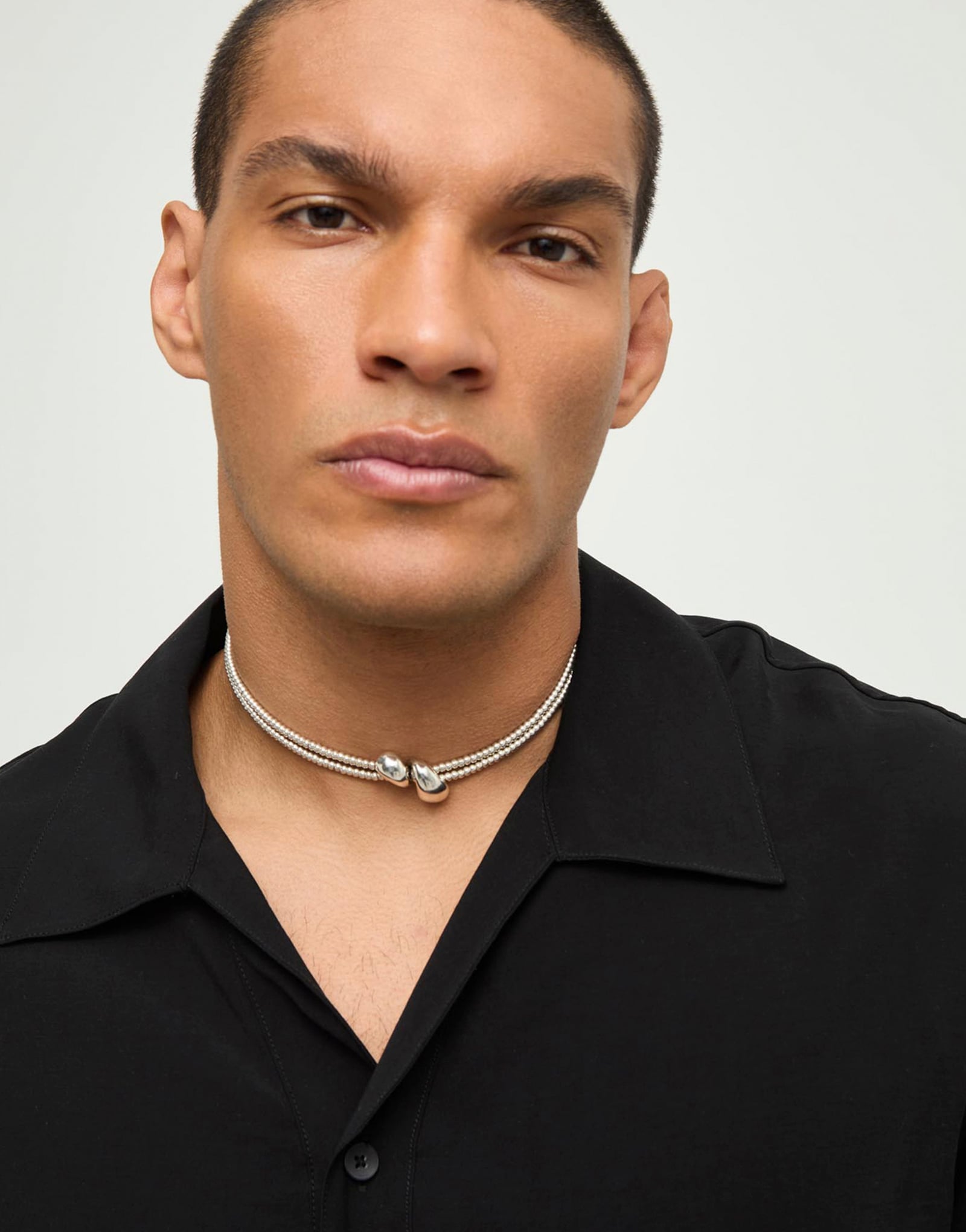 Multi-strand necklace with two intertwined drops